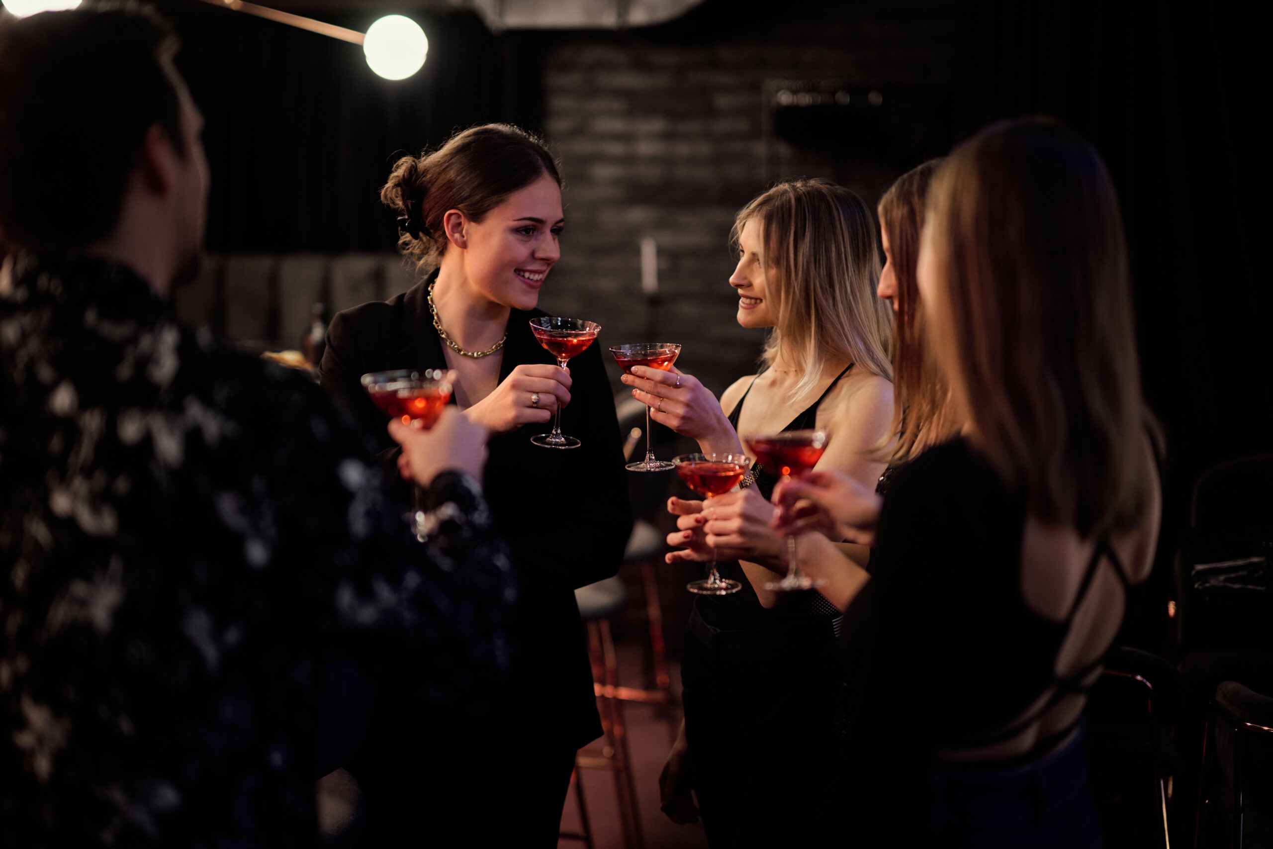 Kollegen beim Anstoßen in einer Bar mit einem roten Drink.